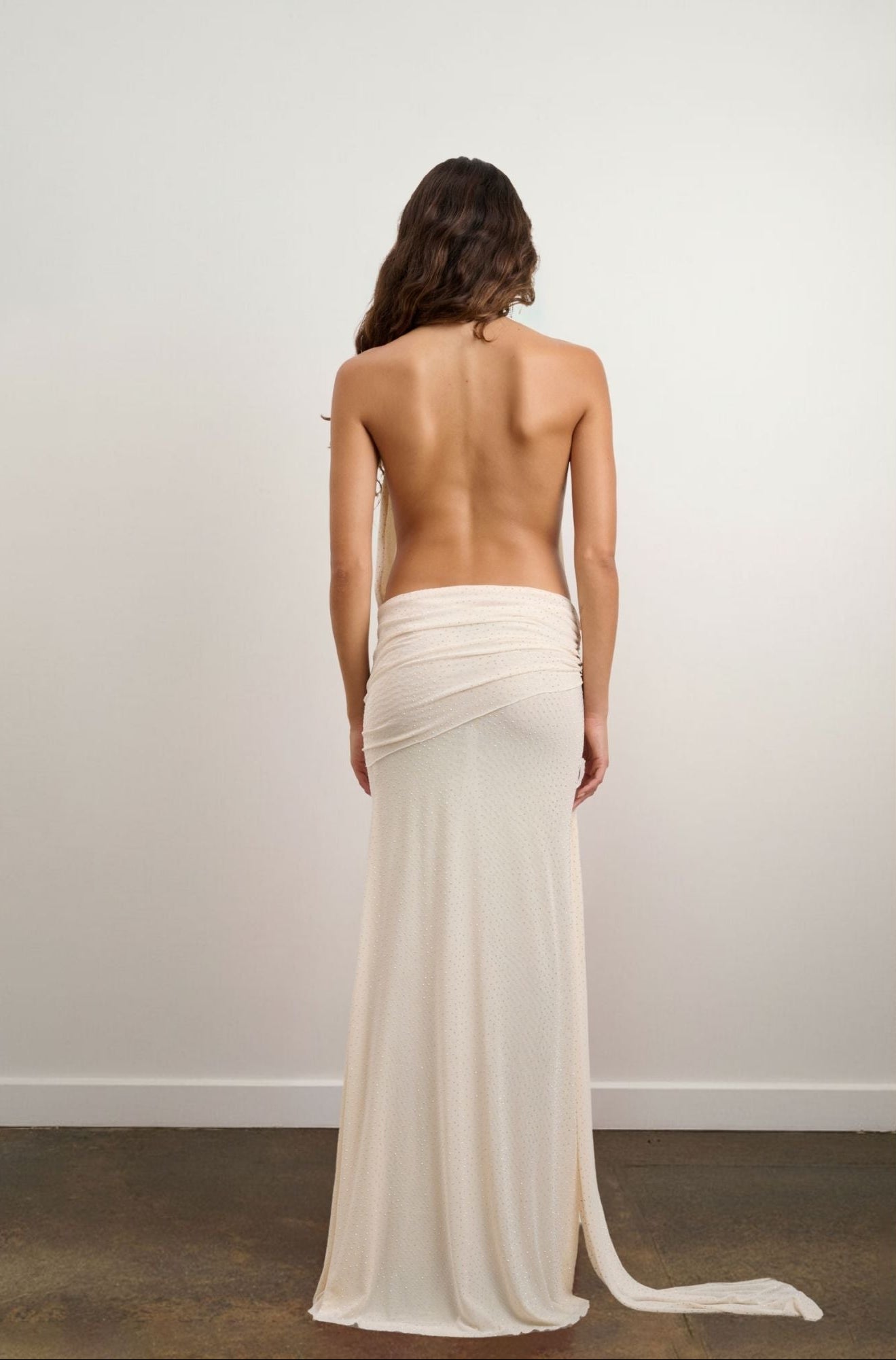 Woman wearing a long, flowing ivory rhinestone mesh dress